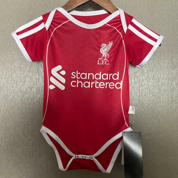 Red baby onesie with white accents and branding on a hanger against a metallic surface.