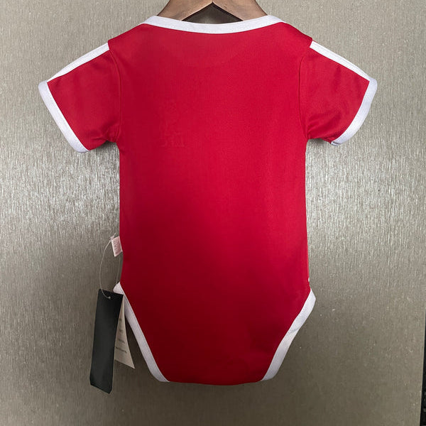 Red baby onesie with white trim on a hanger against a neutral background