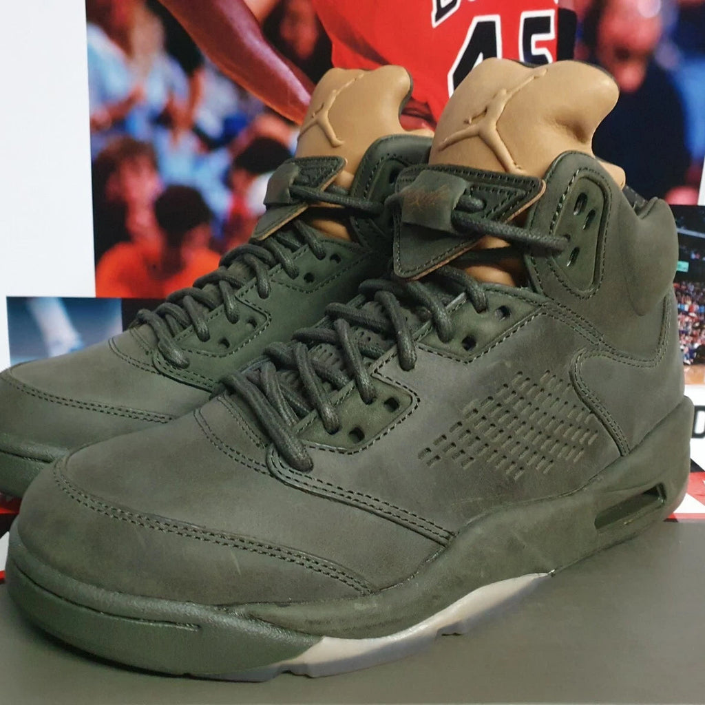 Green high-top sneakers with tan accents on a surface with a sports-themed background.