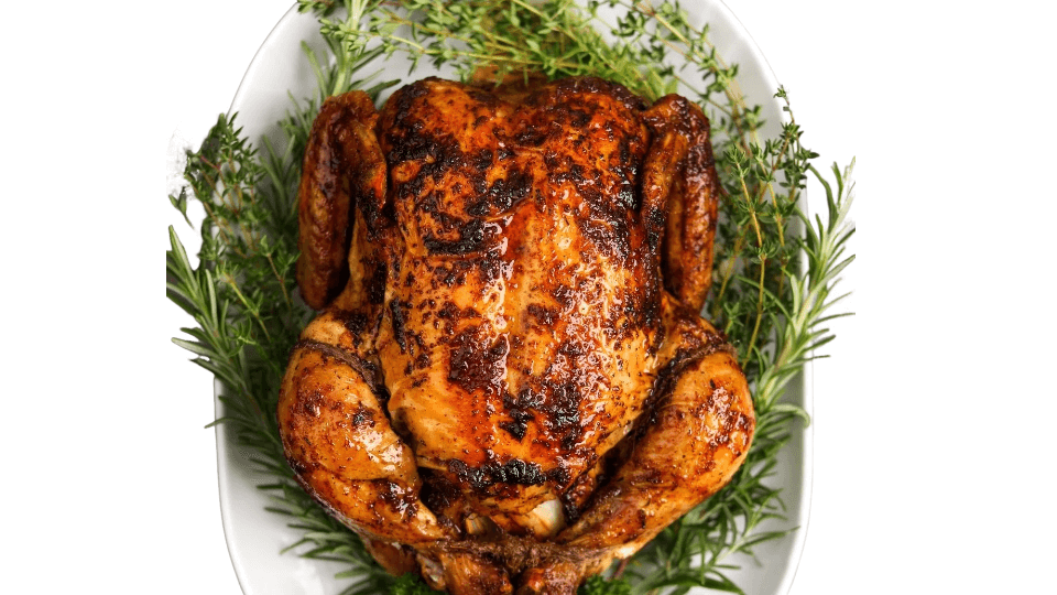 Roasted chicken on a bed of herbs on a white plate. whole roasted chicken from Town Bakery